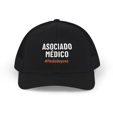 Black trucker hat embroidered with "Asociado Médico" in white text and "#PAsGoBeyond" in orange.