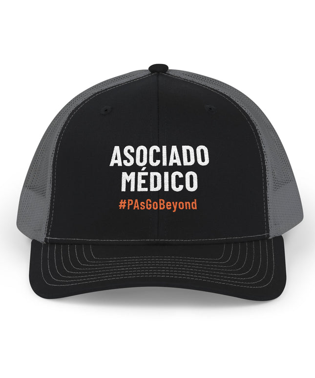 Black and grey trucker hat embroidered with "Asociado Médico" in white text and "#PAsGoBeyond" in orange.