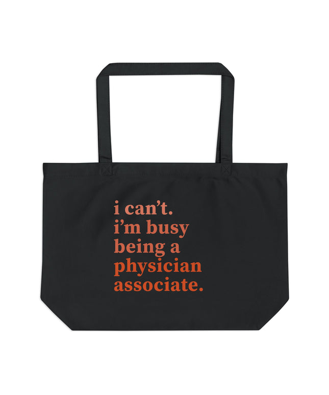 Black canvas tote bag printed with "i can't. i'm busy being a physician associate." in orange text.